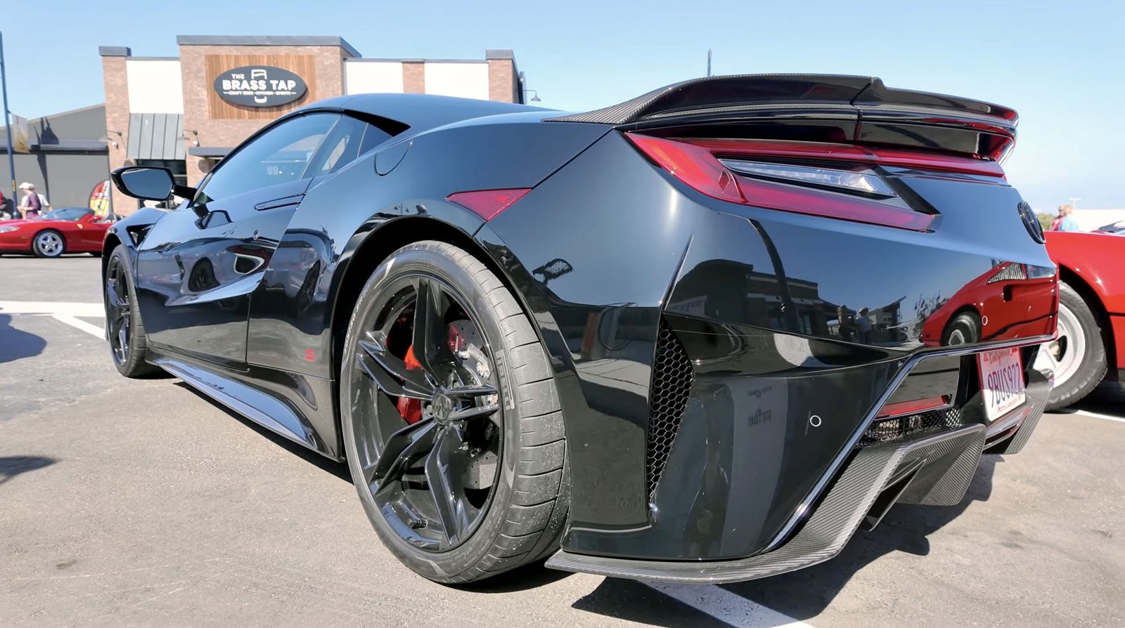 A black Acura NSX with red accents parked at a Monterey Car Week show in Marina