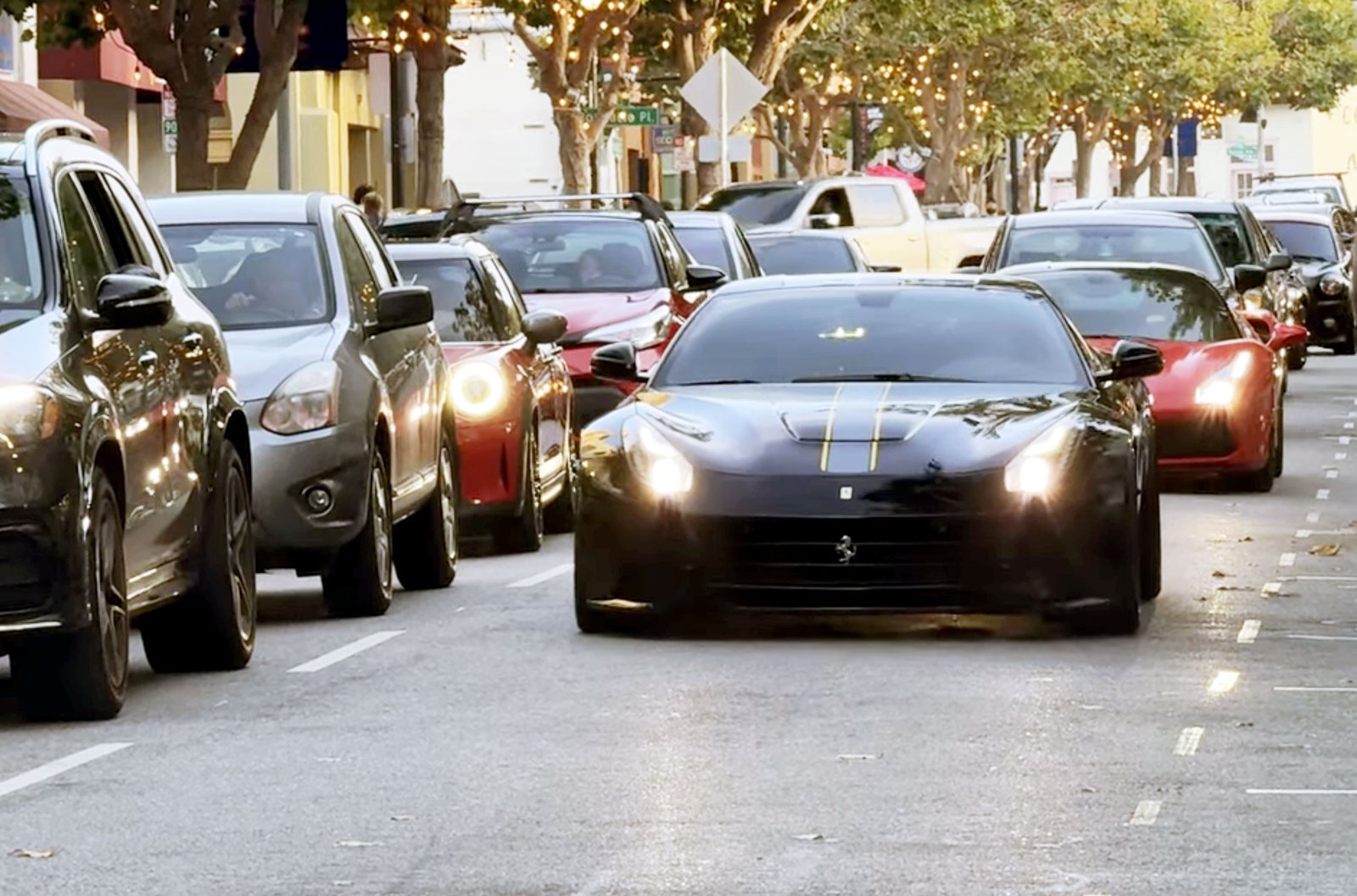 A black Ferrari and a red Ferrari roll down Alvarado Street lined with crowds at the Monterey Car Week kickoff