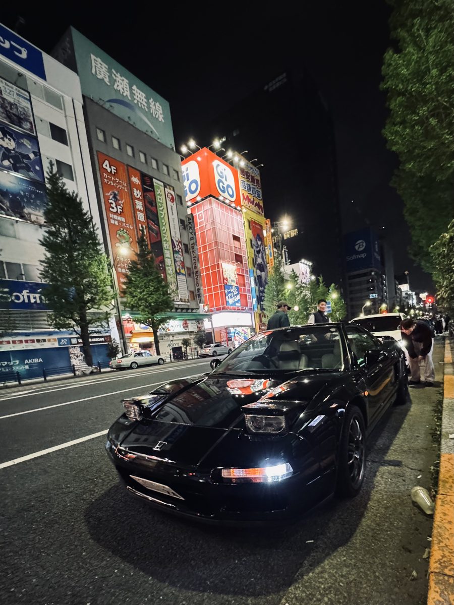 Black Honda NSX with people gathered around it on an Akihabara street at night