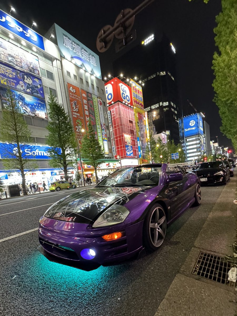 Purple Mitsubishi Eclipse Spyder with a spiderweb hood and teal underglow in Akihabara