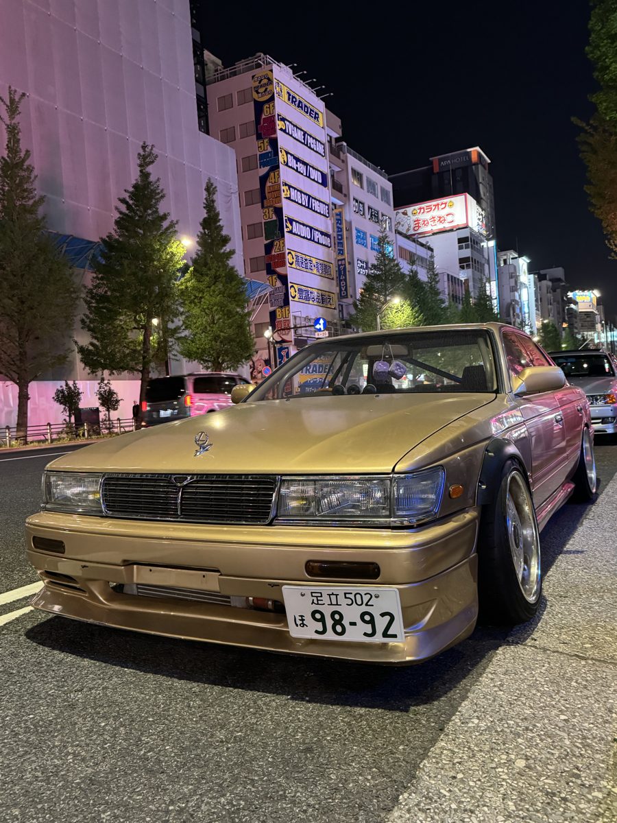 Slammed gold Nissan Laurel C33 with wide fenders on an Akihabara street at night