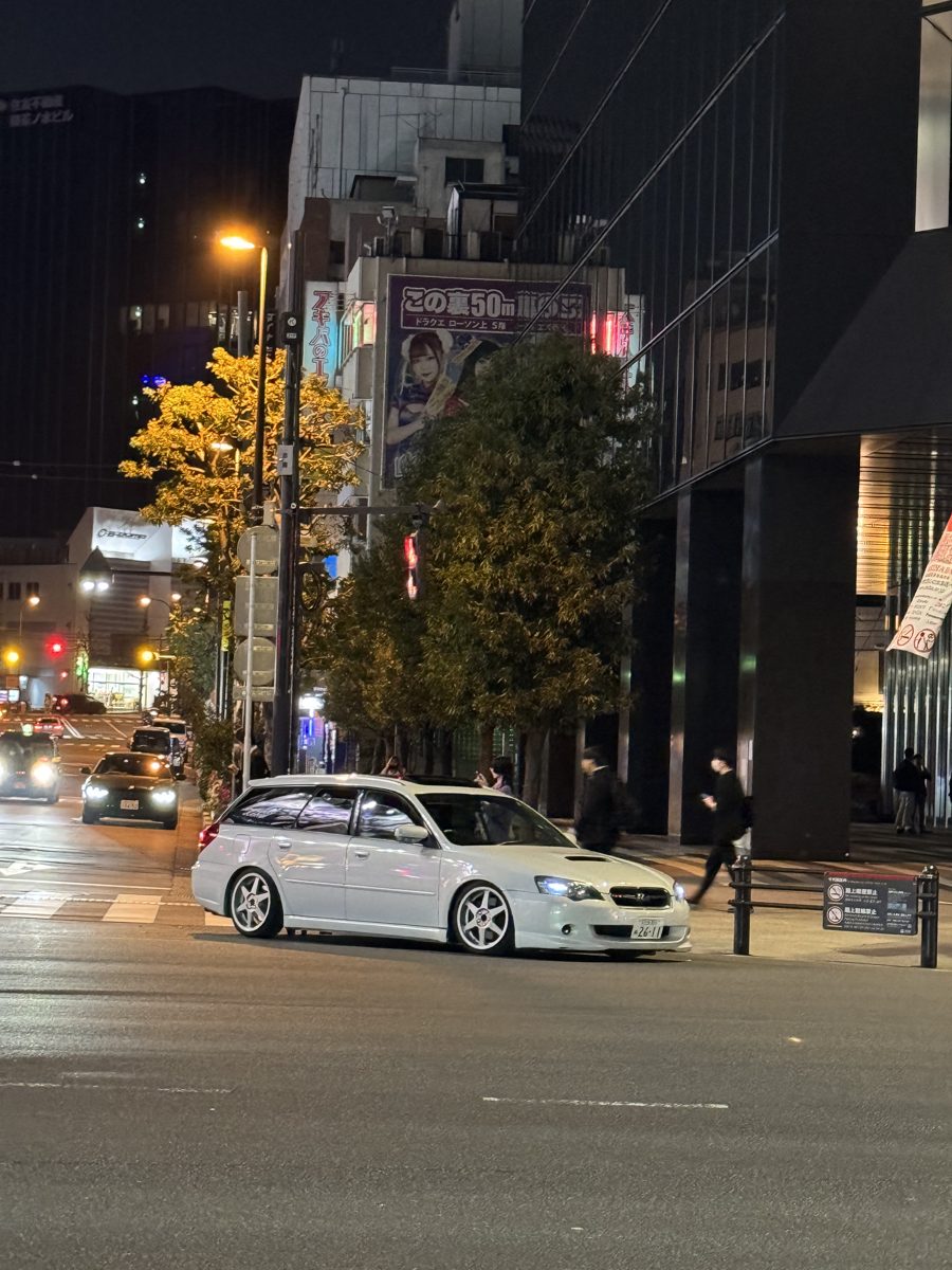 Lowered white Subaru Legacy wagon at an Akihabara intersection at night