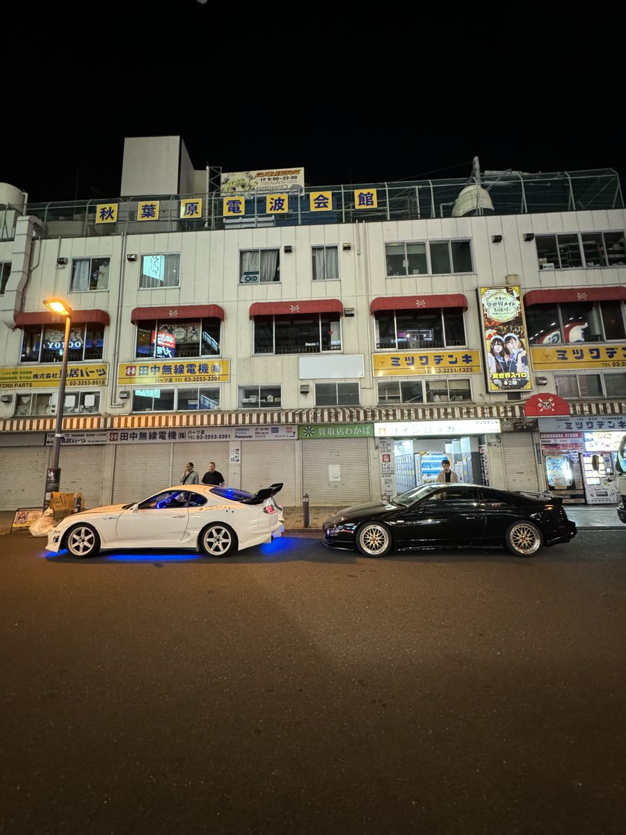 Toyota Supra and Nissan Skyline parked in front of the Akihabara Radio Kaikan at night