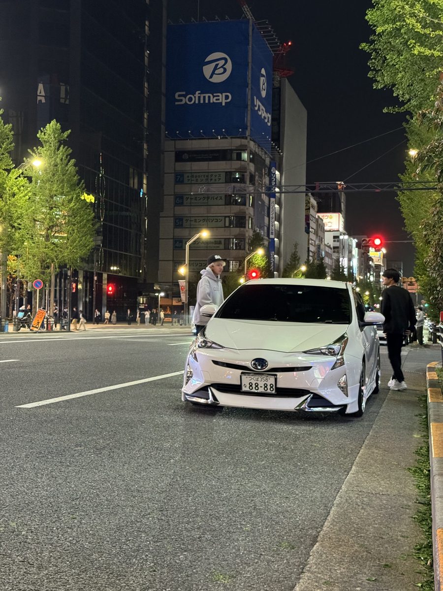 Lowered, body-kitted Toyota Prius with an 88-88 plate in front of the Sofmap building