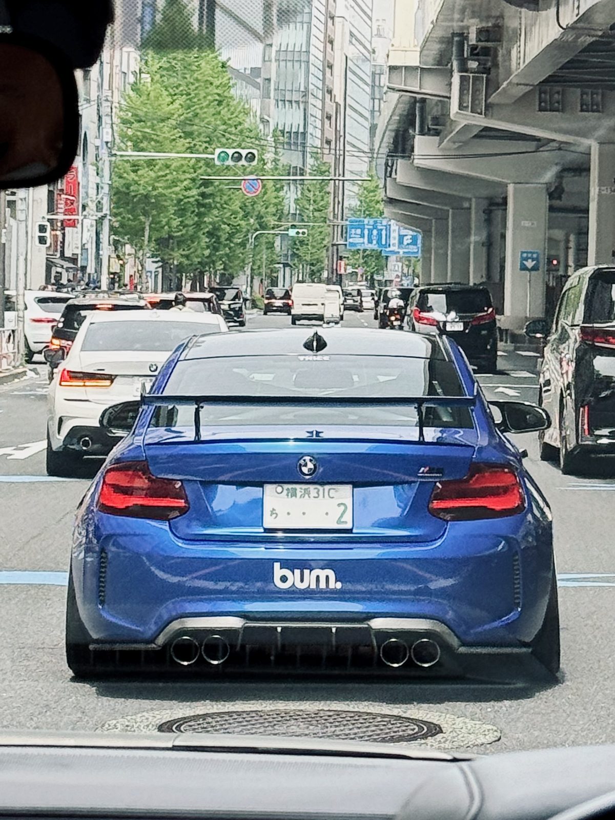 Blue BMW M2 lowered with a wing, spotted in Tokyo traffic, spring 2024