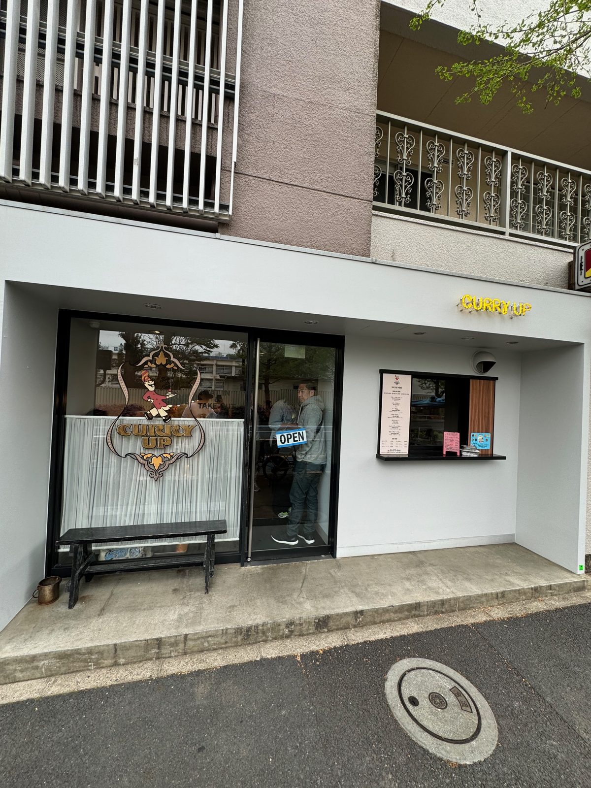 The Curry Up storefront in Tokyo with an OPEN sign and a small menu window